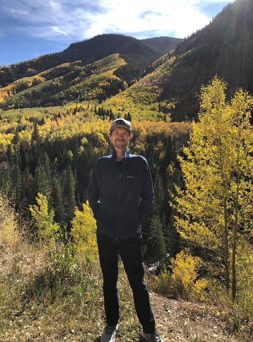 Jason standing with forested hills behind him