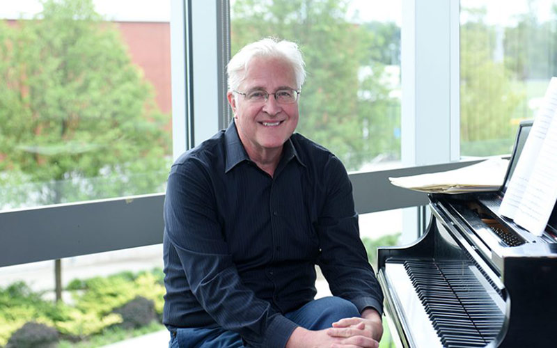 Paul Moravec posing in front of piano