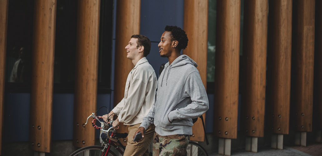 Two men walking, one with a bike