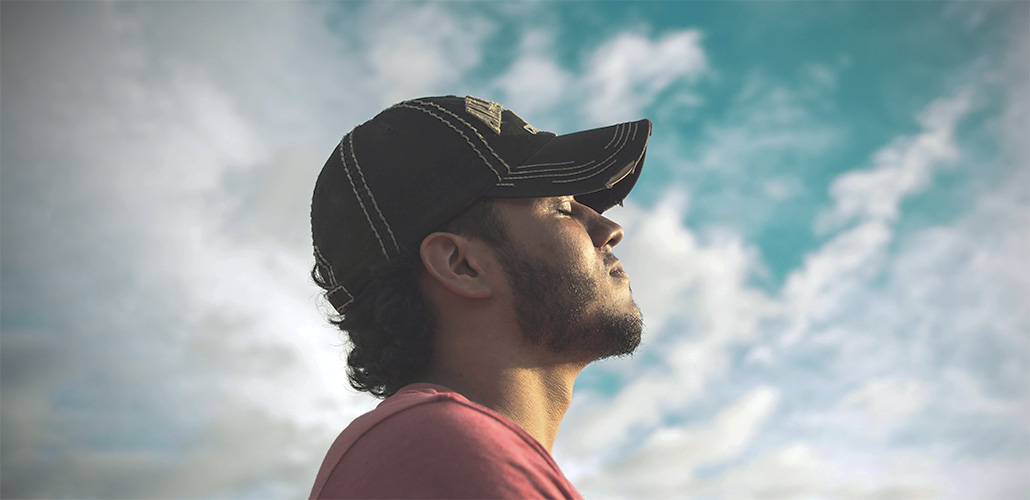 Man taking a deep breath with the sky in the background