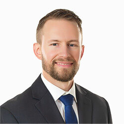 Headshot of Corey Sleep in a suit on a white background