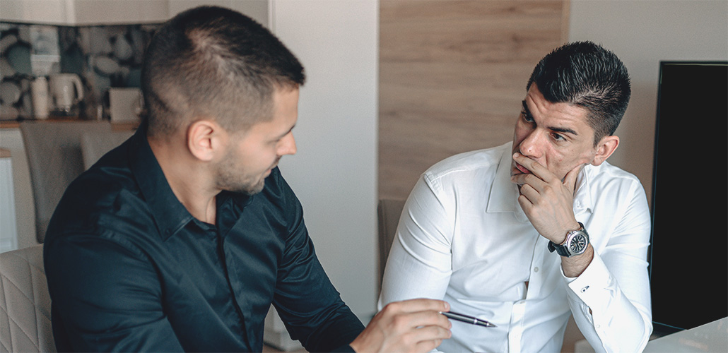 Two men in office attire having a conversation at a table