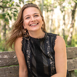 A photo of Julie Long smiling and sitting on a bench outdoors