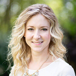 A photo of Kristin Matthews in front of a blurry backdrop of plants