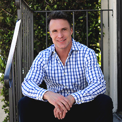 A professional photo of Dr. Greg Cason sitting on some stairs