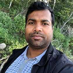 A photo of Mukesh Mishra in front of some greenery outdoors