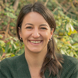 A photo of Erin Green smiling in front of some foliage