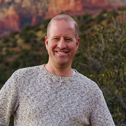 A photo of Jason Fierstein smiling in front of an Arizona landscape